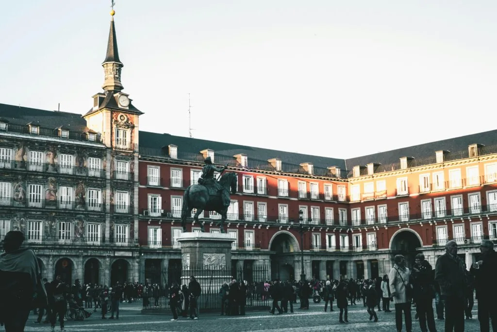A lively scene at Plaza Mayor, Madrid, featuring historic architecture and a statue.