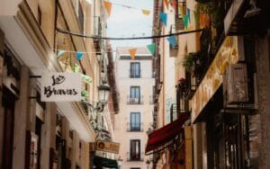 A Guide to Madrid's Festivals Charming Madrid street with vibrant flags and traditional storefronts.